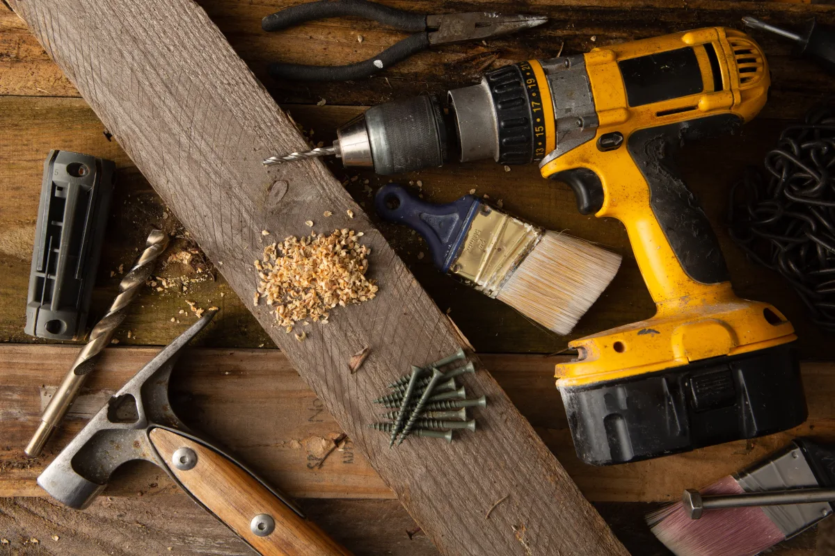 Assorted power tools including a drill and other hand tools on a workbench