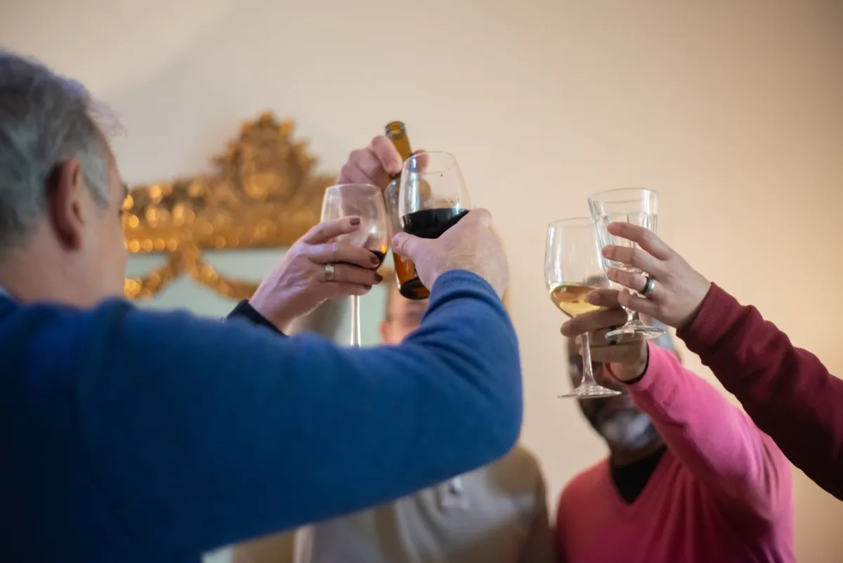 Group raising glasses in joyful beer toast at indoor celebration