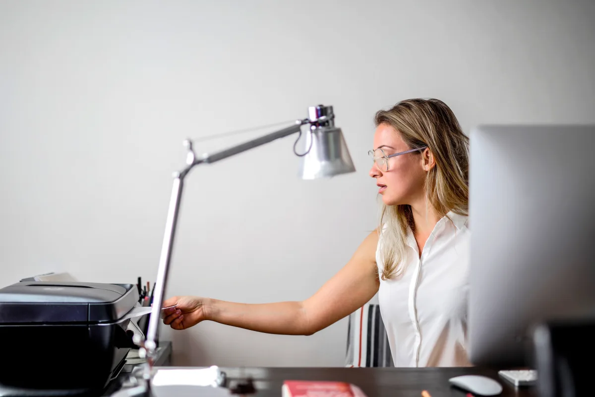 Woman in a modern office using a multifunction all-in-one printer